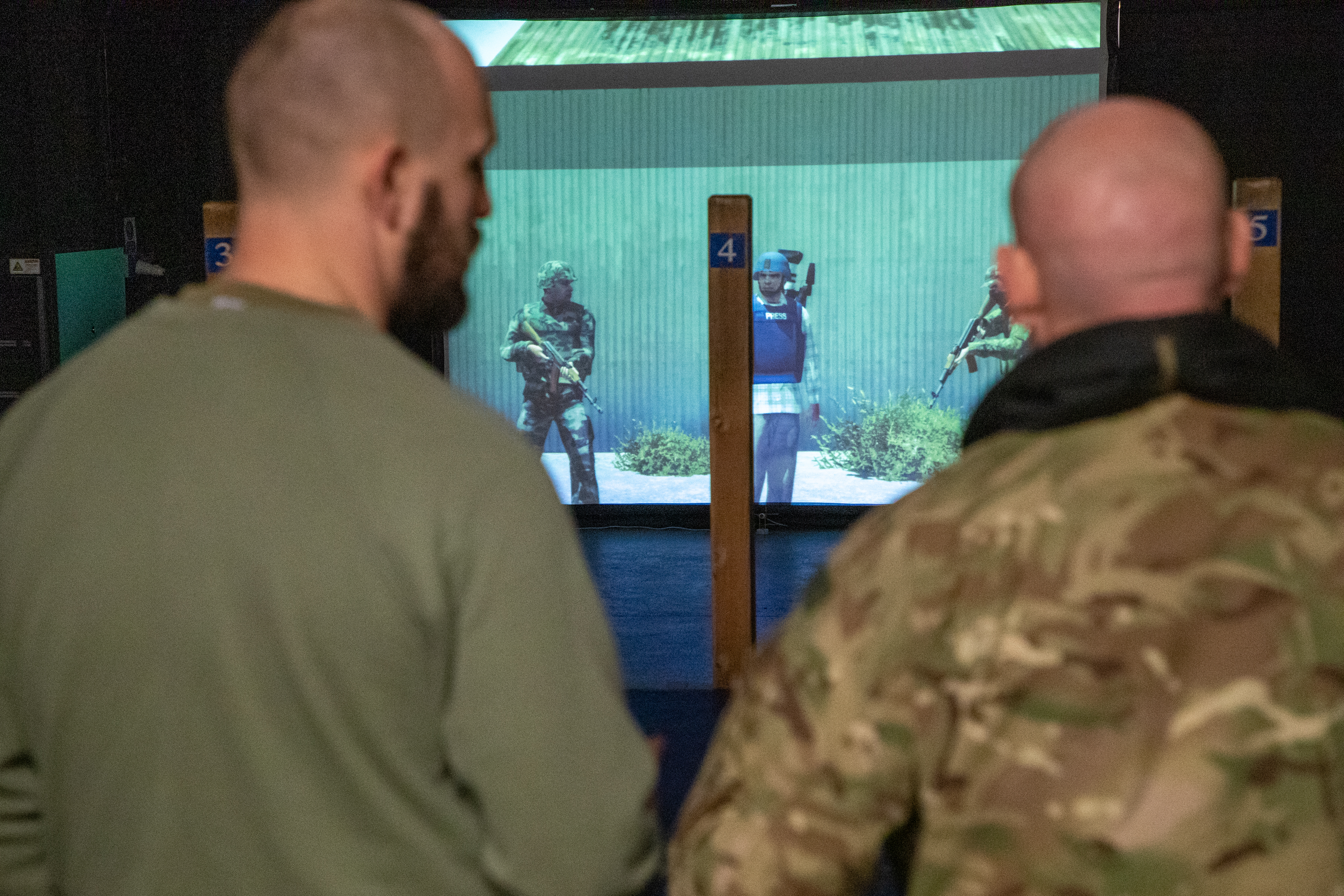 Personnel look at targets on projected screen.